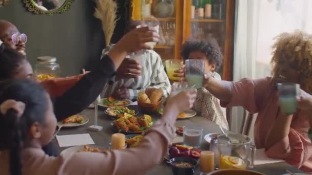Μεγάλες αφρο-αμερικανική οικογένεια clinking ποτήρια σε τοστ και πίνοντας λεμονάδα, ενώ έχοντας σπίτι το δείπνο κόμμα - Πλάνα, βίντεο
