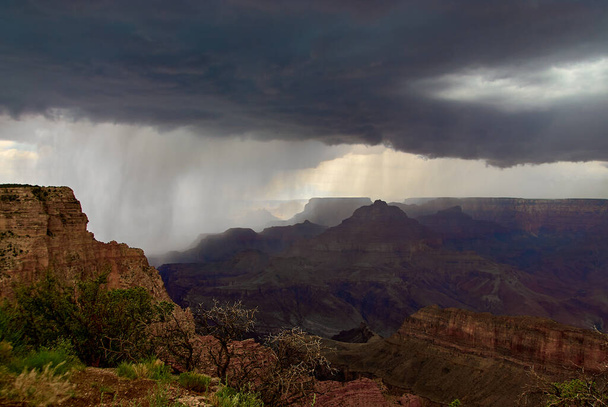 A dramatic photo of a monsoonal thunderstorm dropping a wall of rain over the Grand Canyon on a August afternoon, as seen near Lipan Point on the south rim of canyon in Arizona, USA. - Photo, Image