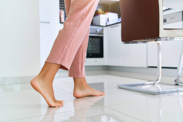 Female barefoot legs on heated warm floor at home kitchen   - Foto, afbeelding