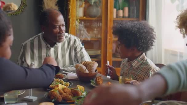 アフリカ系アメリカ人のお父さん家族と一緒に家のディナーパーティーで小さな息子と話す - 映像、動画