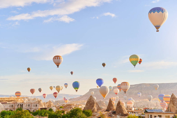 Landscape of fabulous Kapadokya. Colorful flying air balloons in sky at sunrise in Anatolia. Vacations in beautiful destination in Goreme, Turkey  - Foto, afbeelding
