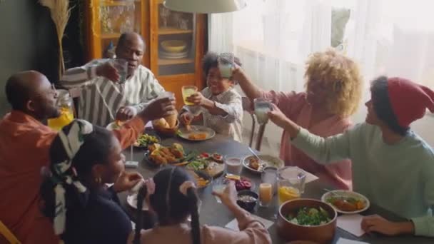 Plan grand angle de grandes afro-américaines famille cliquetis verres en pain grillé et boire de la limonade tout en ayant des vacances dîner à la maison - Séquence, vidéo