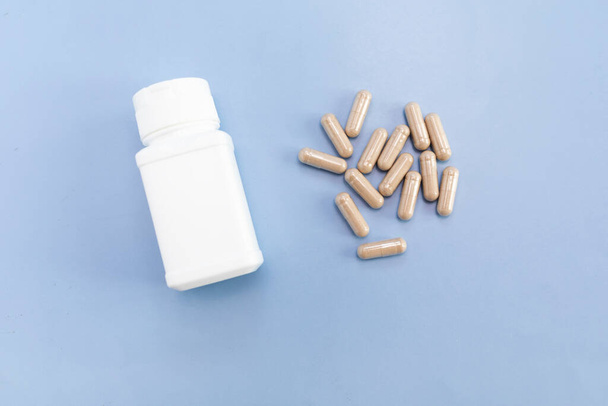 Top View Scattered Pills, Capsules OF Slippery Elm, White Bottle, Container On Blue Background. Dietary Supplement, Medication. Ulmus Fulva, Herbal Remedy Concept. Horizontal Plane. - Photo, Image
