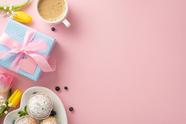 Kreatív Anyák Napja asztalterítő koncepció finom süteményekkel, ajándékokkal, kávéscsészékkel és tulipánokkal, pasztell rózsaszín háttérrel, üres hellyel a személyre szabott üdvözléshez vagy szöveghez - Fotó, kép