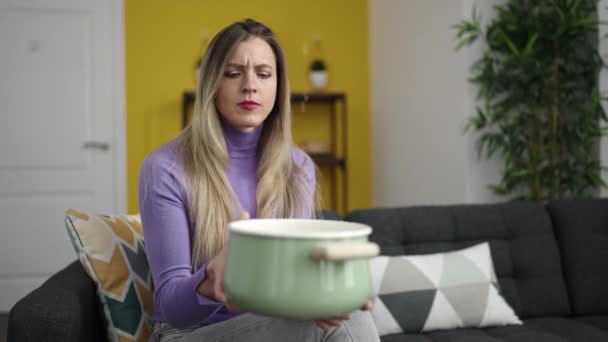 Jeune femme blonde tenant le pot de cuisson pour la fuite d'eau à la maison - Séquence, vidéo