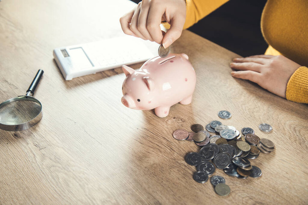 woman hand coins and piggy bank with calculator on the table - Photo, image