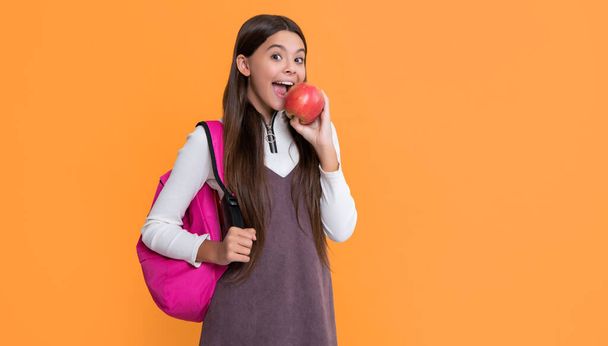 amazed child with school backpack and apple on yellow background. - Photo, Image