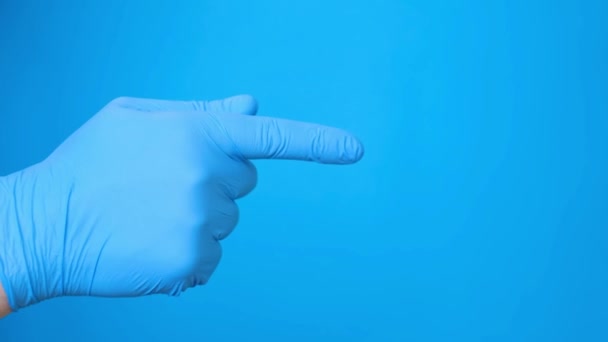 Obrázek ruky v modré lékařské rukavici na modrém pozadí. Ruka s ukazováčkem ukazuje na něco nebo někoho. Lidská gesta rukou - Záběry, video