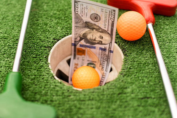 Money, mini golf balls on grass. Concept of sports bet. - Fotó, kép