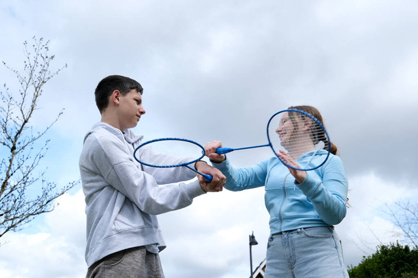 badminton rackets boys girl swing each other with racket background of sky play having fun First love teen relationship angry be satisfied smile emotions transitional age young men and women - Fotografie, Obrázek