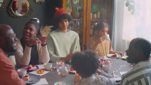 Duży kąt ujęcia dużej Afroamerykańskiej rodziny jedzącej tort urodzinowy i rozmawiającej w domu świątecznej kolacji - Materiał filmowy, wideo
