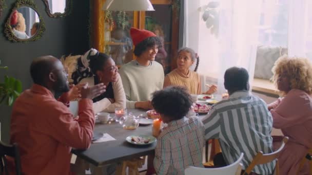 Plan grand angle d'une grande famille afro-américaine en train de manger et de parler tout en dînant ensemble à la maison - Séquence, vidéo