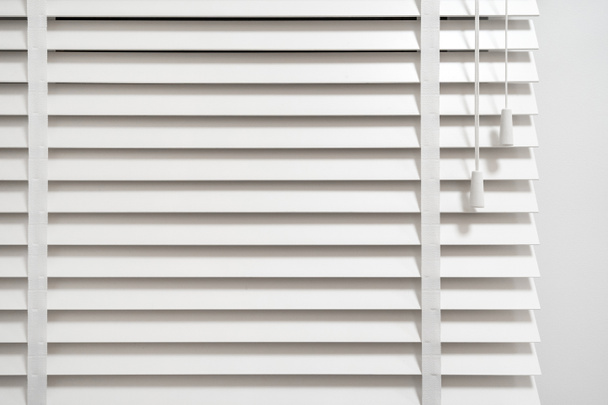 Traditional louvers in venetian style, close up. Window blinds with horizontal wooden slats in modern living room. Concept of privacy and sunlight protection in apartment - Фото, изображение