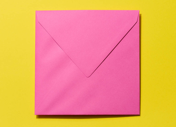 Square pink envelope on a yellow background - Foto, imagen