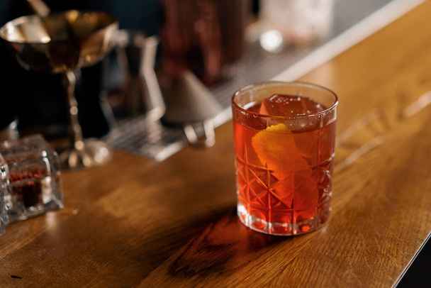 Крупный план готового вкусного алкогольного коктейля Негрони стоит на барной стойке и ждет гостей - Фото, изображение