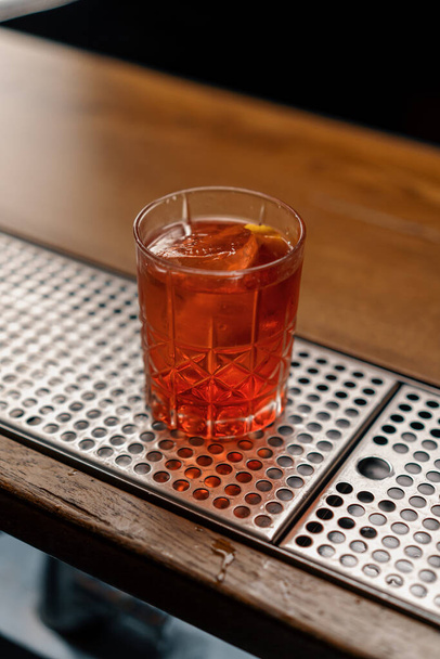 A close-up of the ready-made delicious alcoholic cocktail Negroni is standing on the bar and waiting for guest - Photo, Image