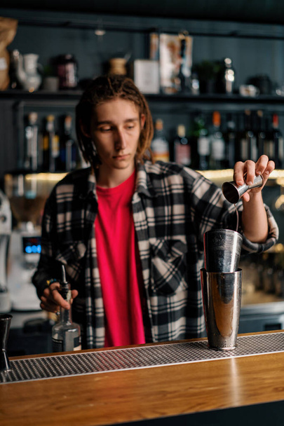Um barman experiente derrama líquido em uma coqueteleira com a ajuda de um jigger prepara um coquetel na boate - Foto, Imagem