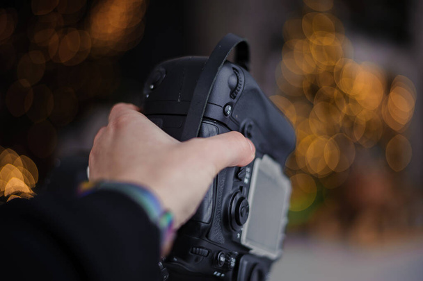 Schwarze Kamera in Frauenhand, schönes Bokeh im Hintergrund - Foto, Bild