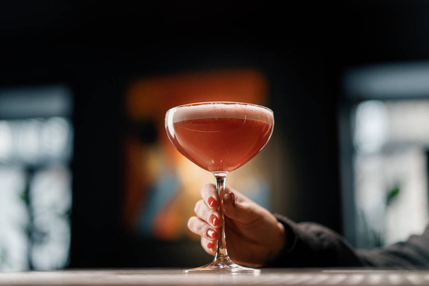 customer holding delicious pink freshly made raspberry milk punch cocktail in hand bar drinks concept - 写真・画像