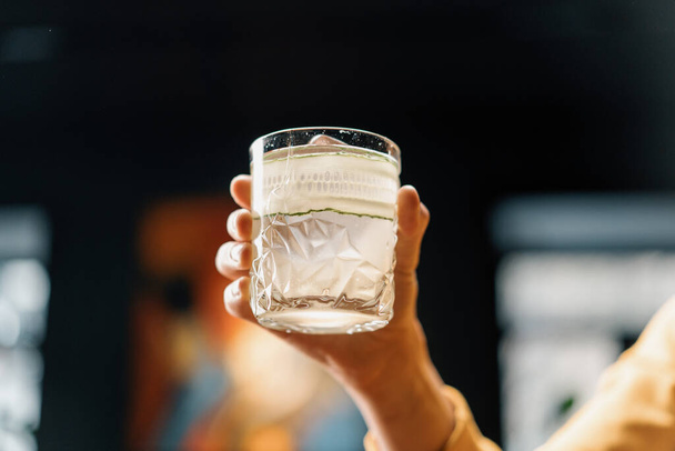 Zákazník drží lahodné čerstvě vyrobené gin zahradní koktejl s okurkou v ruce bar nápoje koncept - Fotografie, Obrázek