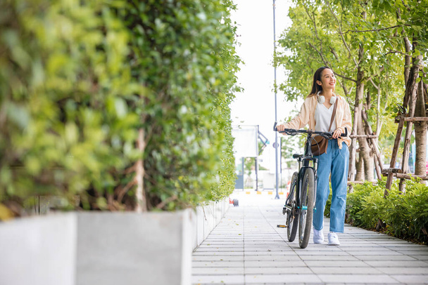 Ευτυχισμένο θηλυκό χαμογελώντας με τα πόδια κάτω από το δρόμο με το ποδήλατό της στο δρόμο της πόλης, ECO περιβάλλον, Lifestyle ασιατική νεαρή γυναίκα με τα πόδια παράλληλα με το ποδήλατο για το καλοκαίρι στην ύπαιθρο, υγιή ταξίδια - Φωτογραφία, εικόνα