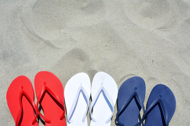 Tongs rouges blanches et bleues sur le sable Beaucoup de place pour votre texte
 - Photo, image