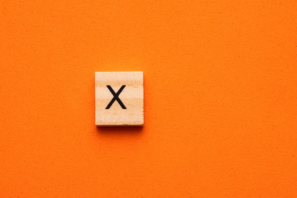 Alfabeto letra maiúscula X em azulejo quadrado de madeira - Fundo espumoso laranja - Foto, Imagem
