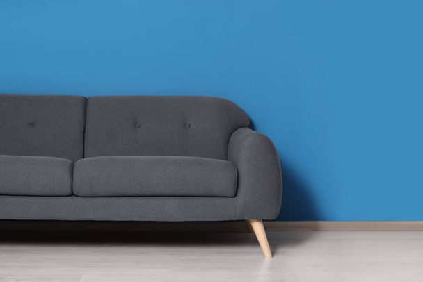 Stylish grey sofa near blue wall in room. Interior design - Photo, image