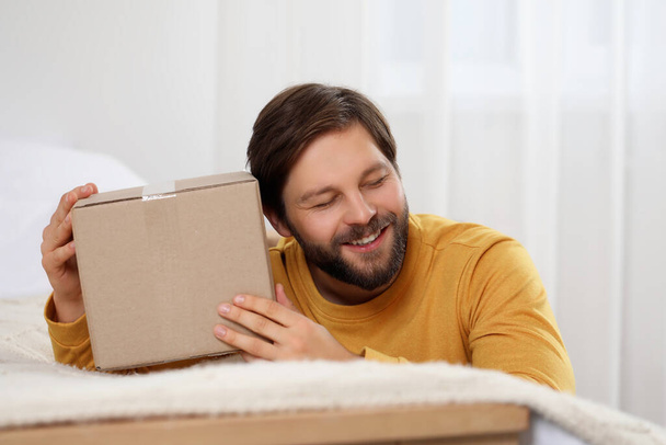 Happy man with parcel at home. Internet shopping - Foto, Imagem