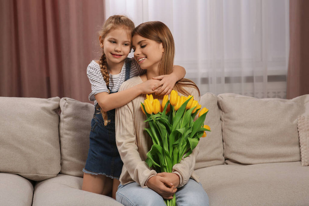 Little daughter congratulating mom with bouquet of yellow tulips at home. Happy Mother's Day - Foto, Bild