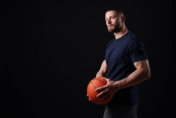 Athletic young man with basketball ball on black background. Space for text - Photo, Image