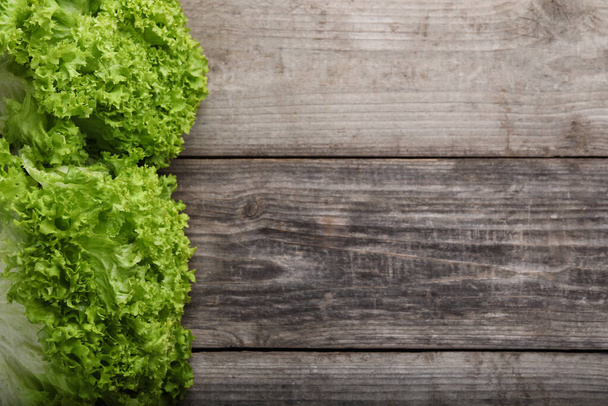 Fresh lettuce on wooden table, flat lay and space for text. Salad greens - Fotoğraf, Görsel