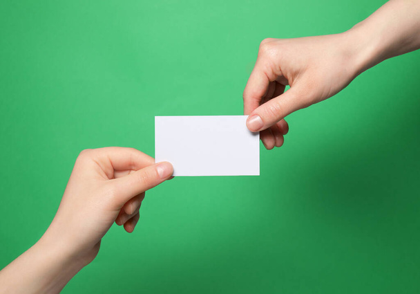 Women holding blank gift card on green background, closeup - Фото, зображення