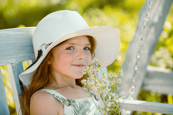 Cute little child girl picking flowers in blooming summer garden. Spring child face. Happy little child with flowers on the grass in a summer. Cute little child on the meadow in backyard - Foto, afbeelding
