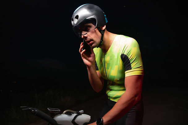 A triathlete using a smartphone while taking a break from a hard nights cycling training. High quality photo - Fotó, kép