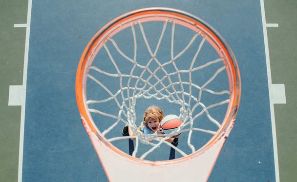 Kid playing basketball. Cheerful boy basketball player holding game ball - Fotografie, Obrázek