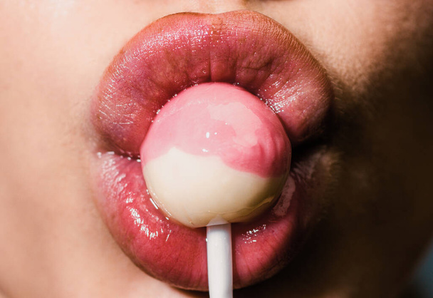 Sexy girl sucks lollipop, close up. Suck lolli pop concept. Woman sucking cute sweet candy closeup lips tongue. Sexy sweet dreams. Female mouth licks chupa chups - Фото, изображение