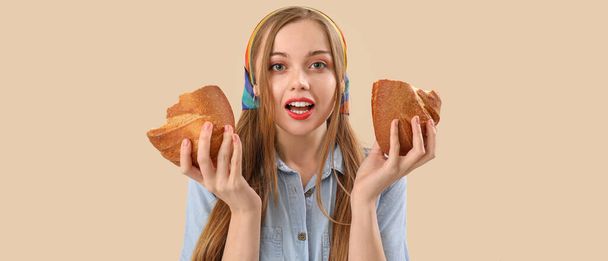 Érzelmi fiatal nő darab friss kenyér bézs háttér - Fotó, kép