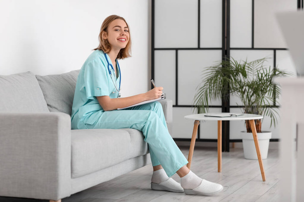 Asistente médica sentada en un sofá en una clínica moderna - Foto, imagen