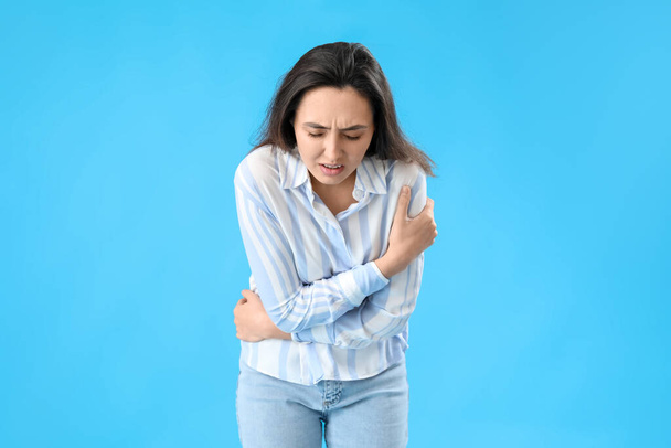 Jonge vrouw met appendicitis op blauwe achtergrond - Foto, afbeelding