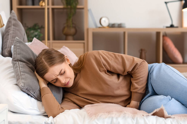 Young woman with appendicitis lying in bedroom - Foto, Bild