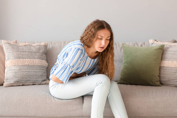 Mladá žena s apendicitidou sedí doma na pohovce - Fotografie, Obrázek