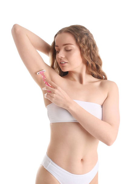 Young woman shaving her armpit with razor on white background - Фото, изображение