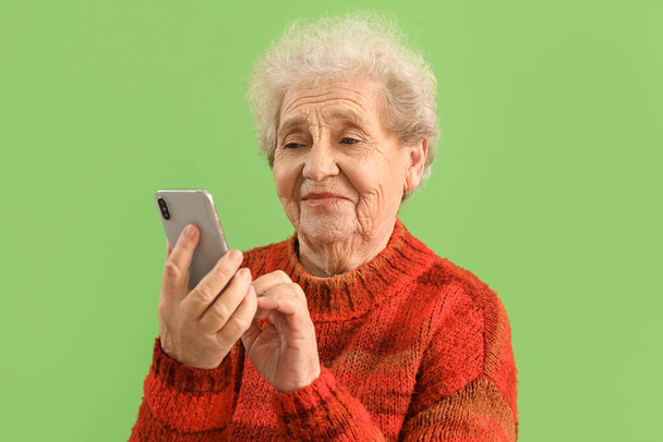 Senior mulher usando telefone celular no fundo verde, close-up - Foto, Imagem