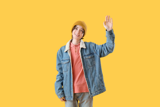 Teenage boy waving hand on yellow background. Hello concept - Foto, Imagem