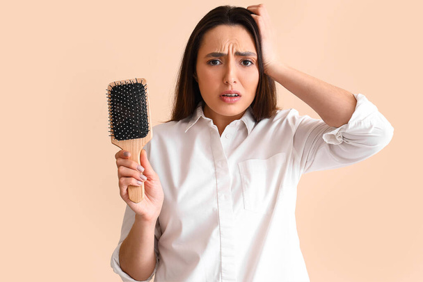 Preoccupato giovane donna con problema di perdita di capelli su sfondo beige - Foto, immagini