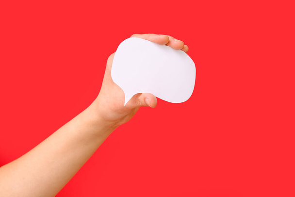 Woman holding blank speech bubble on red background - Foto, afbeelding