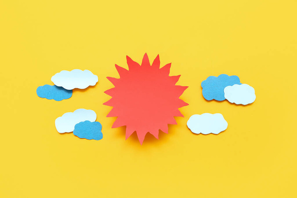 Composition with paper sun and clouds on yellow background - Foto, imagen