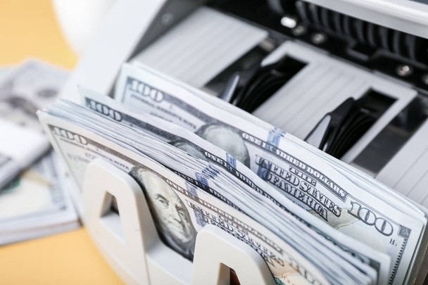Máquina de contagem de dinheiro moderna com notas de dólar em fundo amarelo, close-up - Foto, Imagem