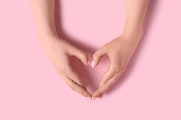 Γυναίκα που κάνει την καρδιά με τα χέρια της σε ροζ φόντο - Φωτογραφία, εικόνα